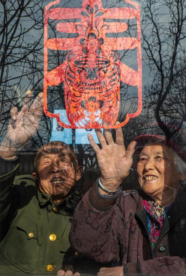臘月里，霍州市師莊鄉(xiāng)馮南垣村村民師榮光(左)在災(zāi)后重建的新家里貼窗花。(霍州市委宣傳部供圖)