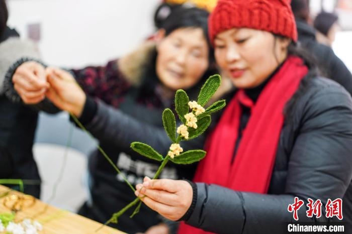 馮燕霞指導(dǎo)姐妹們鉤織月桂葉片。　古良駒 攝