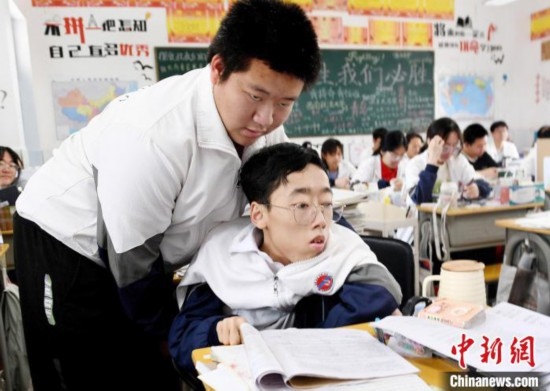 朱金祥(左)把鐘華強放到課堂座位上后，都要把他擺正好，確認安全后才回到自己的座位上。 卓忠偉 攝