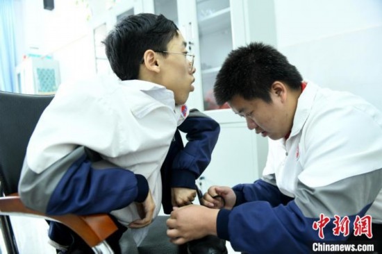 江西省南康中學北校區(qū)的高三學生朱金祥(右)正在給鐘華強(左)系好鞋帶。 卓忠偉 攝