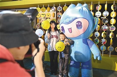 5月7日，在浙江省杭州市湖濱步行街“3D笑臉墻”前，攝影師為游客與杭州亞運(yùn)會(huì)吉祥物之一“宸宸”拍攝合影。