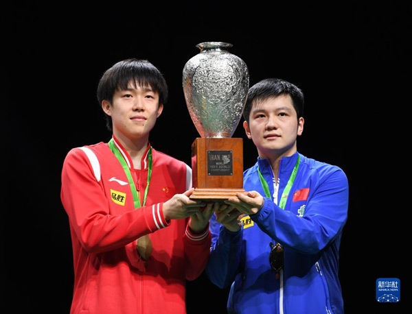 5月27日，樊振東（右）/王楚欽在頒獎儀式上高舉獎杯慶祝。當(dāng)日，在南非德班進行的2023年世界乒乓球錦標(biāo)賽男雙決賽中，中國組合樊振東/王楚欽以3比0戰(zhàn)勝韓國組合張禹珍/林鐘勛，奪得冠軍。新華社記者 李亞輝攝
