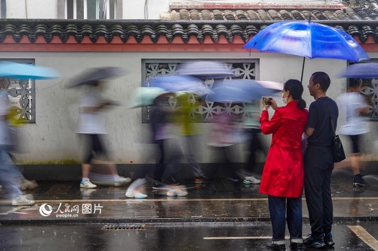 6月7日，在浙江省2023年普通高校招生考試鎮(zhèn)海中學(xué)考點，家長冒雨目送子女進入考場。人民網(wǎng) 章勇濤攝