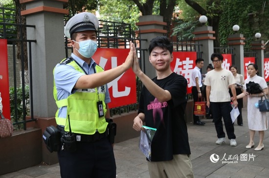 6月7日8時許，武漢中學(xué)考點門口，交警在維護秩序，并?？忌鸢耦}名。人民網(wǎng)記者 肖璐欣攝