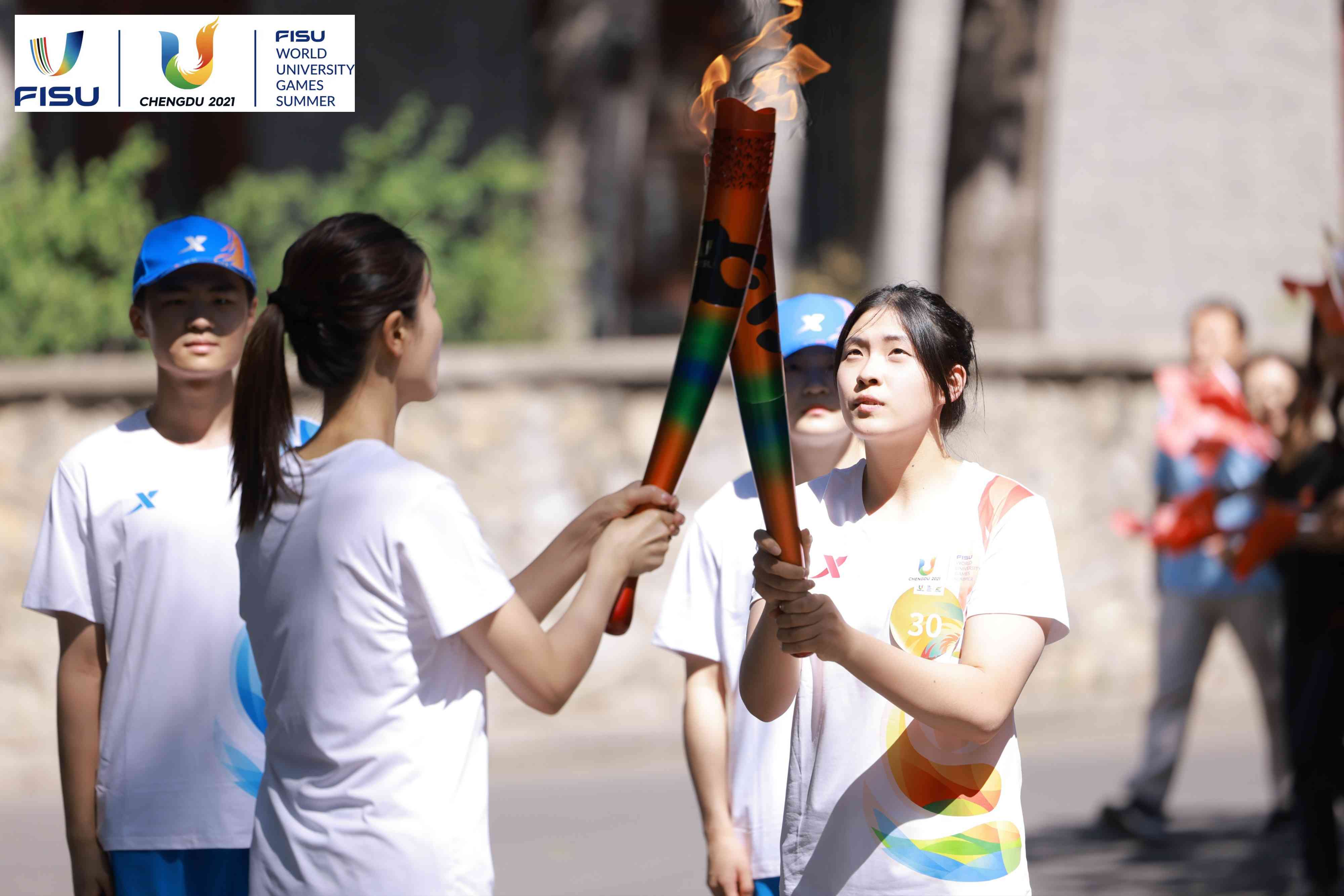 兩名大運(yùn)會火炬手進(jìn)行火炬?zhèn)鬟f。 圖片來源：成都大運(yùn)會執(zhí)委會供圖