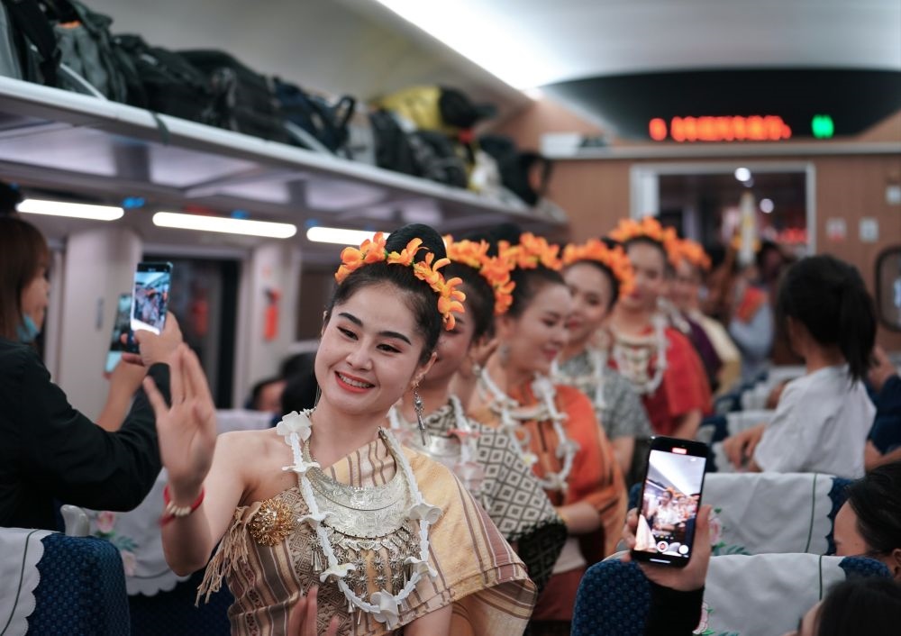 2023年4月13日，老撾工作人員在D887次國(guó)際旅客列車上表演。當(dāng)日，中老鐵路從中國(guó)昆明南站、老撾萬象站雙向?qū)﹂_D887次和D888次國(guó)際旅客列車，兩地乘火車可當(dāng)日通達(dá)。中老鐵路是高質(zhì)量共建“一帶一路”的標(biāo)志性工程。新華社記者 邢廣利 攝