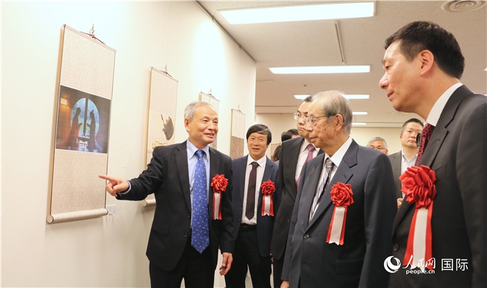 “湖州印象”攝影展主創(chuàng)、世界華人攝影協(xié)會(huì)副會(huì)長(zhǎng)馮學(xué)敏向吳江浩大使、福田康夫前首相等嘉賓介紹展出作品。（人民網(wǎng) 許可攝）
