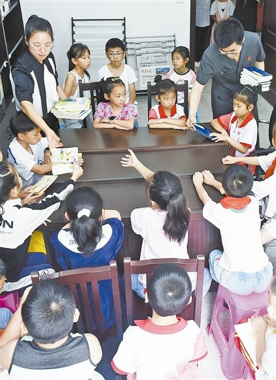  圖④：法院干警為留守兒童發(fā)放暑假讀物。