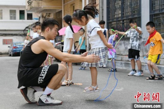 圖為大學(xué)生志愿者在教孩子們學(xué)跳繩。廖光福 攝