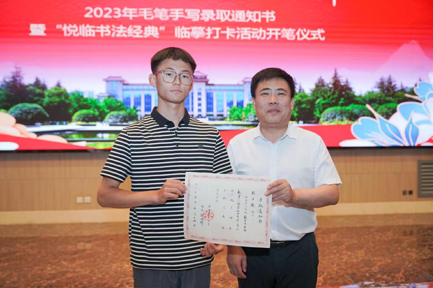 陜西師范大學黨委書記李忠軍為2023級新生代表張占彪同學發(fā)放錄取通知書。校方供圖