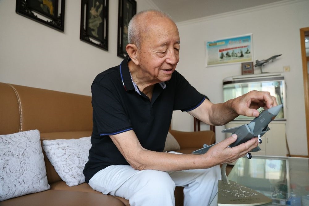 ↑2023年7月24日，新中國(guó)第一代飛行員陶偉在家中擦拭殲-20飛機(jī)模型。新華社發(fā)（張瑞 攝）