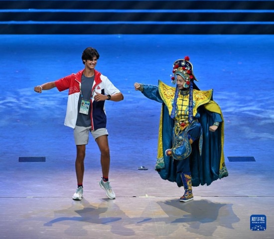 7月29日，美國運動員杜恩（左）在聯(lián)歡會現(xiàn)場與川劇演員互動。新華社記者 蔡湘鑫 攝