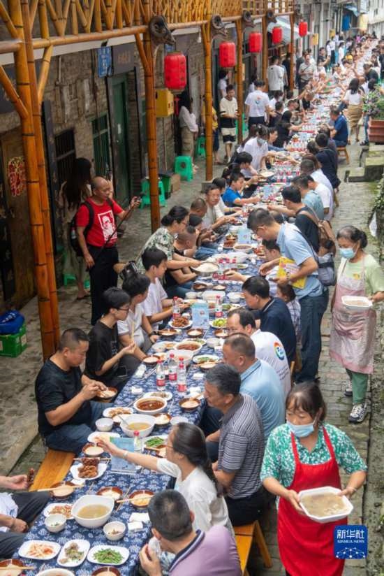 7月29日，在重慶市綦江區(qū)安穩(wěn)鎮(zhèn)，人們在“苗家伏羊節(jié)”上吃長桌宴。新華社記者 唐奕 攝