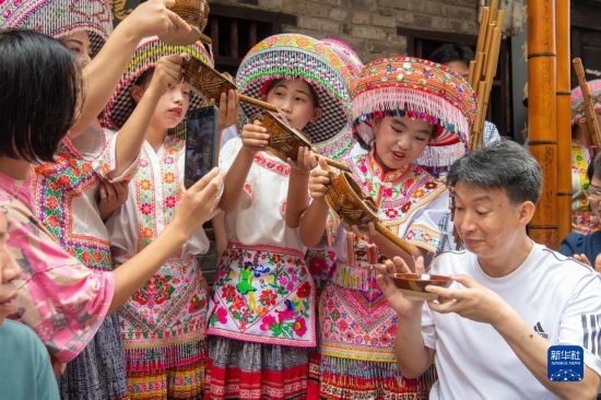 7月29日，在重慶市綦江區(qū)安穩(wěn)鎮(zhèn)，當(dāng)?shù)鼐用裨凇懊缂曳蚬?jié)”上用傳統(tǒng)習(xí)俗向游客表達祝福。新華社記者 唐奕 攝