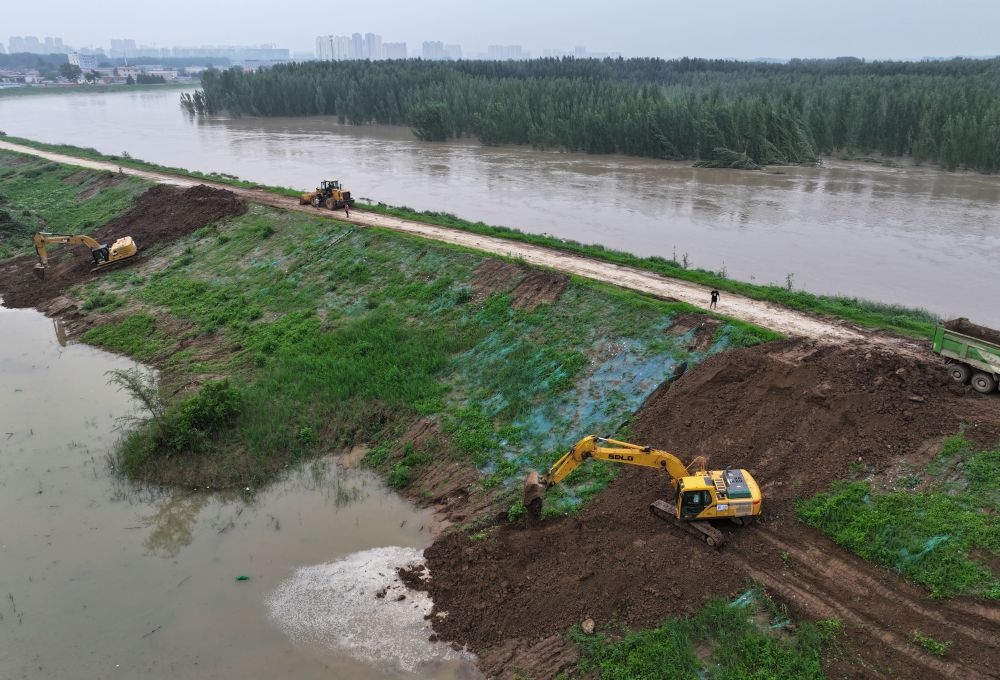 工人操作機(jī)械在白溝河左堤白溝新城高橋村段進(jìn)行除險(xiǎn)加固作業(yè)（8月4日攝，無(wú)人機(jī)照片）。新華社記者 朱旭東 攝