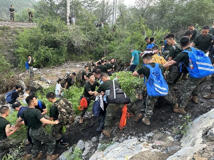 8月2日，Z180次受困列車的旅客在武警北京總隊(duì)機(jī)動(dòng)第三支隊(duì)官兵的幫助下徒步前往轉(zhuǎn)運(yùn)客車（手機(jī)照片）。新華社記者 王艷剛 攝