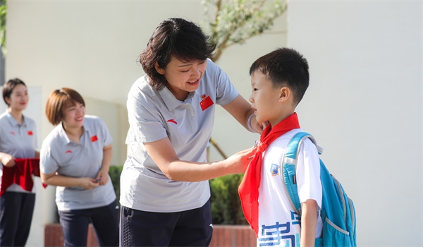 8月30日，雄安史家胡同小學(xué)學(xué)生體驗(yàn)學(xué)校生活。老師為學(xué)生佩戴?；?。