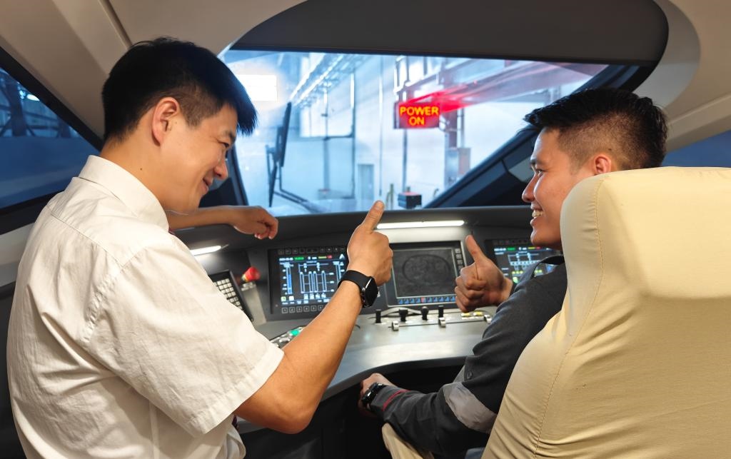8月25日，在印度尼西亞萬隆的雅萬高鐵德卡魯爾動車所內(nèi)，中國師傅穆振（左）在向印尼火車司機塞蒂亞萬講解動車組出庫前的上電作業(yè)。