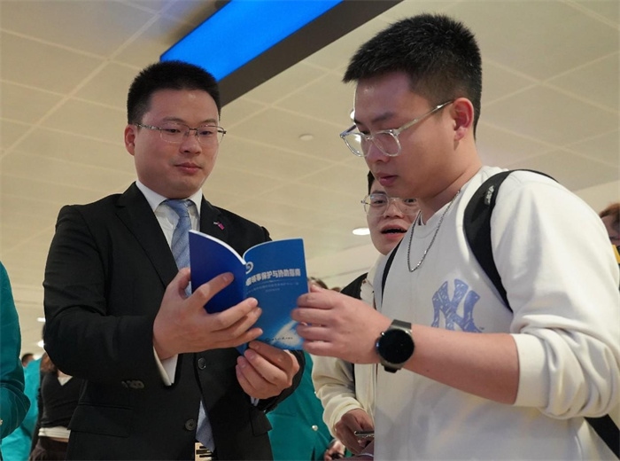 工作人員（左一）在發(fā)放《中國(guó)領(lǐng)事保護(hù)與協(xié)助指南》。 中國(guó)駐迪拜總領(lǐng)事館供圖