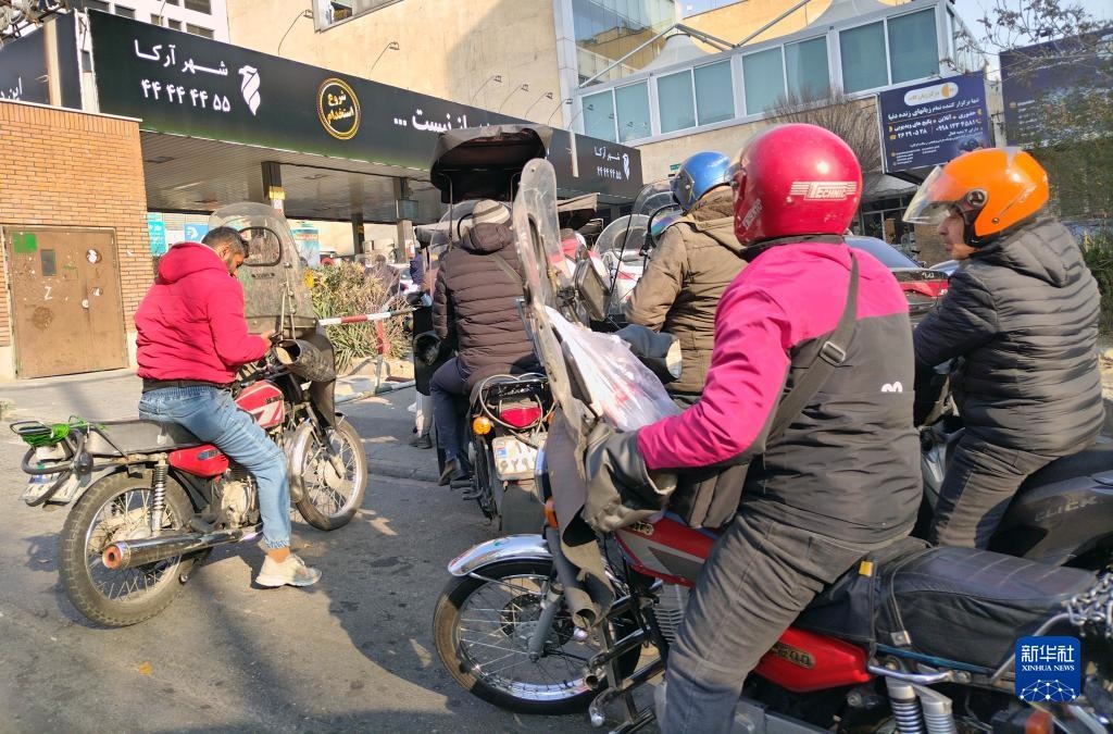 12月18日，摩托車在伊朗首都德黑蘭的一家加油站外等待加油。新華社記者 沙達提 攝
