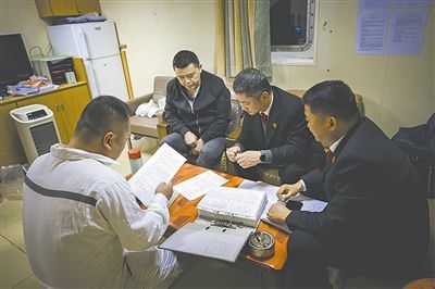圖②：法官向船長講解相關(guān)法律規(guī)定，查看船舶資料，并與船方辦理扣押船舶的手續(xù)。