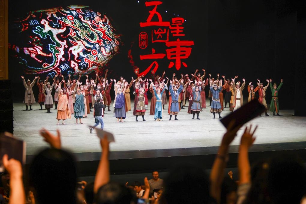 2023年7月31日，新疆和田地區(qū)新玉歌舞團(tuán)在烏魯木齊京劇院演出舞劇《五星出東方》后和觀眾互相揮手致意。這場演出是第六屆中國新疆國際民族舞蹈節(jié)的參演劇目之一，曾榮獲國家“文華獎”等。新華社記者 郝昭 攝
