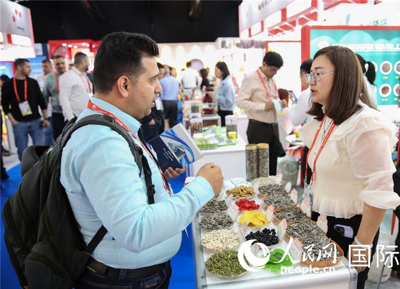 圖為一家中國(guó)干果參展企業(yè)代表與采購商洽談。人民網(wǎng) 塔里克·易卜拉欣攝