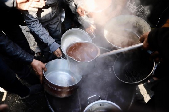  2月27日，在加沙地帶北部的杰巴利耶難民營，人們領(lǐng)取食物。新華社發(fā)（穆罕默德·阿里攝）