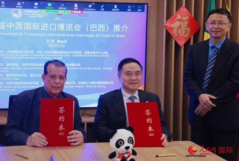 巴西外貿(mào)商會聯(lián)合會會長阿代爾·羅伯托（左）與中國國際進(jìn)口博覽局副局長吳政平（中）現(xiàn)場簽訂協(xié)議。人民網(wǎng)記者 宋亦然攝