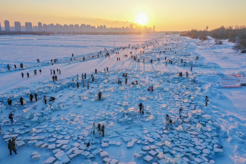 2024年1月7日，在封凍的松花江哈爾濱段，游客在日落時(shí)分的“鉆石海”游玩（無(wú)人機(jī)照片）。新華社記者 謝劍飛 攝