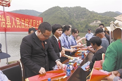 法院干警及相關(guān)部門工作人員對(duì)群眾進(jìn)行生態(tài)環(huán)境保護(hù)普法教育。
