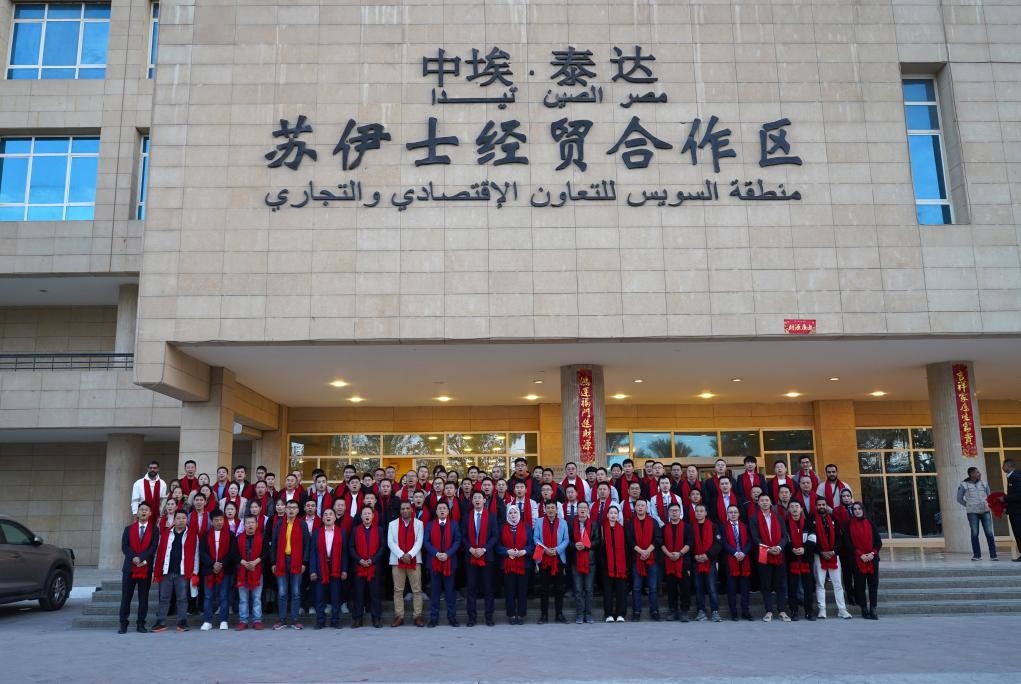 2024年2月11日，在位于埃及蘇伊士省的中埃·泰達蘇伊士經(jīng)貿(mào)合作區(qū)，中埃員工在合作區(qū)辦公大樓前合影拜年。新華社發(fā)（泰達合作區(qū)供圖）
