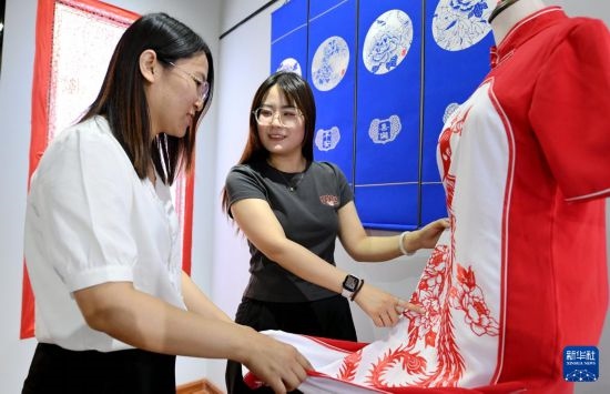 5月31日，在衡水市阜城縣一家剪紙工作室，游客在觀賞帶有剪紙元素的旗袍。