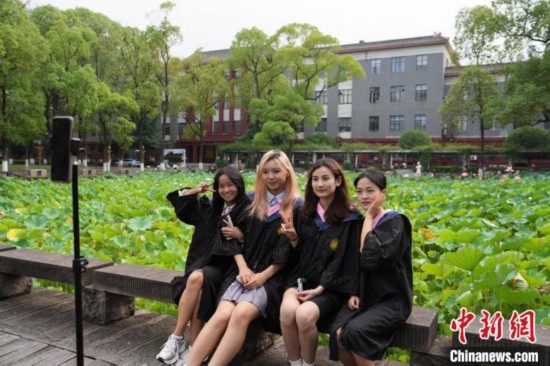 6月19日，時(shí)值一年畢業(yè)季，四川大學(xué)望江校區(qū)荷花池里的荷花盛開，成為了畢業(yè)生們的打卡圣地，吸引了眾多畢業(yè)生拍照留念。圖為畢業(yè)生在荷花池邊拍照留念。中新社記者 安源 攝