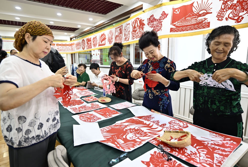 6月19日，長城花園社區(qū)居民在社區(qū)“才藝堂”制作剪紙。