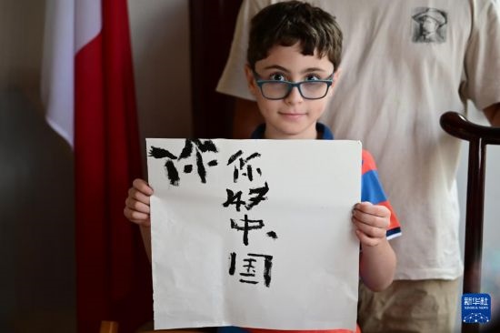 7月4日，在馬耳他桑塔露琪亞市的中國古典園林“靜園”，一名男孩展示他的書法作品。新華社發(fā)（喬納森·博格 攝）