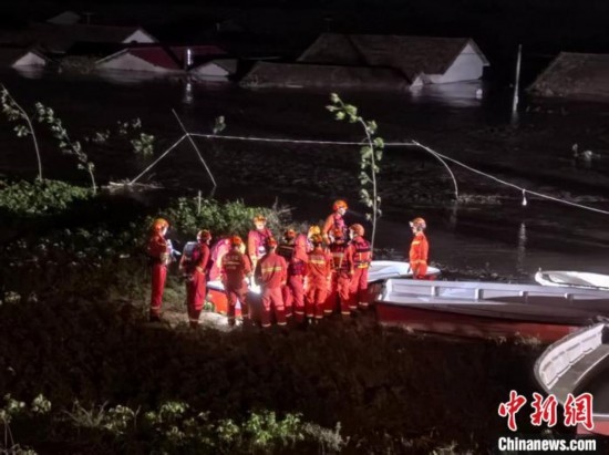  7月6日凌晨3時，在湖南岳陽華容縣團洲垸洞庭湖一線堤防，救援人員剛剛完成一次救援任務(wù)，遠處是被淹的民房。中新社記者 白祖偕 攝