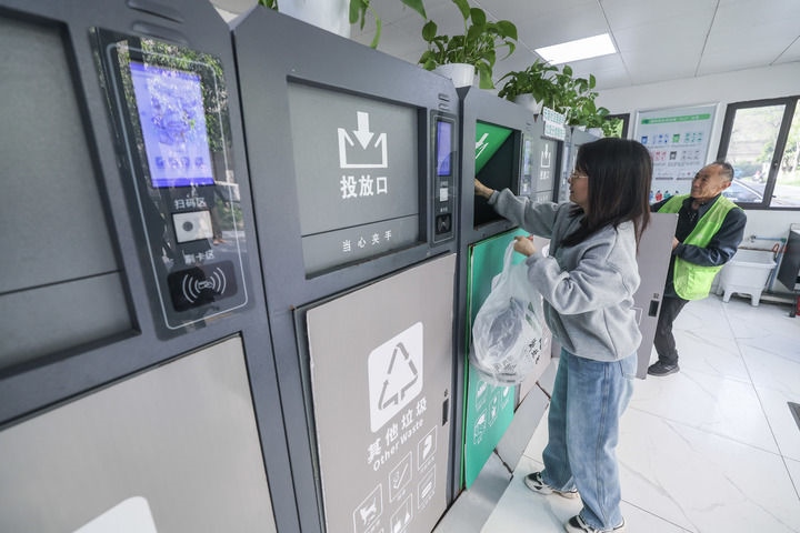 2024年4月10日，在浙江省湖州市吳興區(qū)飛英街道新華府小區(qū)內(nèi)，居民在垃圾分類智能系統(tǒng)的指導(dǎo)下進(jìn)行垃圾分類投放，居民的投放情況將實(shí)時(shí)匯總到智慧服務(wù)平臺(tái)，會(huì)有相應(yīng)的積分獎(jiǎng)勵(lì)。新華社記者 徐昱 攝