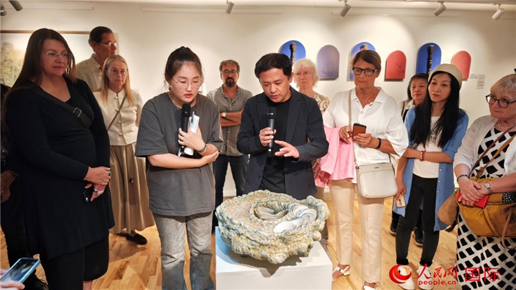 參展人、景德鎮(zhèn)陶瓷大學(xué)設(shè)計(jì)藝術(shù)學(xué)院副院長余劍峰（中）向來賓介紹參展作品。人民網(wǎng)記者 殷淼攝