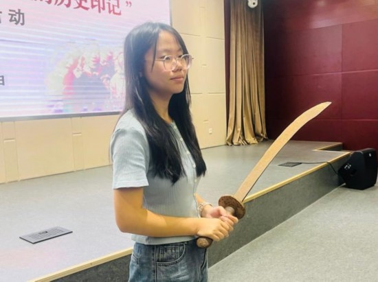 圖為南開大學(xué)社會實踐隊學(xué)生代表呼月紅在學(xué)術(shù)交流活動現(xiàn)場，展示河間調(diào)研行中獲贈的一戰(zhàn)華工蔡世春曾使用過的一把大刀。林卓瑋 攝