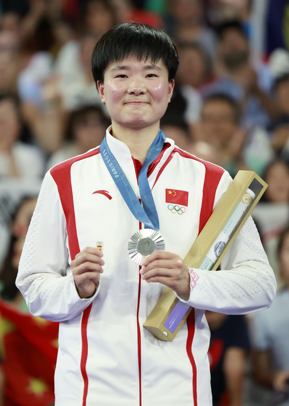 巴黎奧運(yùn)會(huì)羽毛球女子單打亞軍、中國(guó)選手何冰嬌在頒獎(jiǎng)儀式上一手握著銀牌，一手握著西班牙奧委會(huì)徽章（2024年8月5日攝）。新華社記者 任正來(lái) 攝