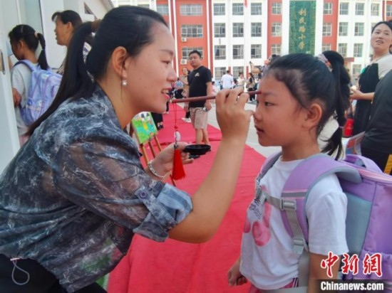 圖為衡水市利民路小學(xué)，老師為學(xué)生點(diǎn)朱砂痣，寓意開啟智慧。張松 攝