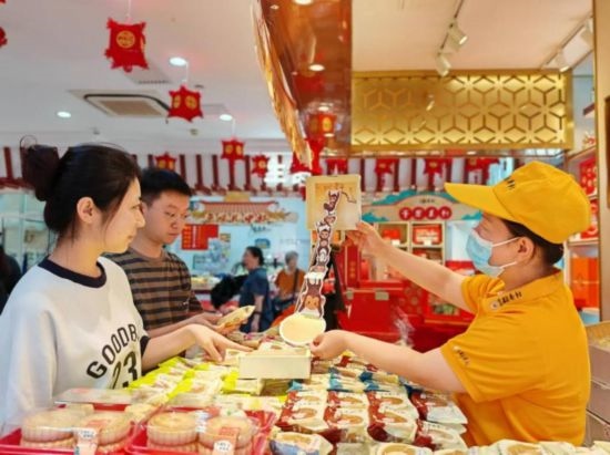 北京稻香村一家門店內(nèi)，售貨員向顧客展示新上市的月餅禮盒。（受訪者供圖）