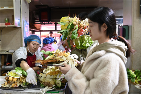 游客挑選好麻辣燙菜品后排隊等待加工。新華社記者 范培珅 攝