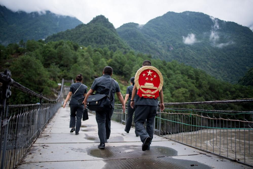 云南省怒江傈僳族自治州貢山縣人民法院法官鄧興背著國徽與同事們跨過怒江（2019年8月30日攝）。怒江高山峽谷眾多，交通不便，為方便群眾、更好地開展法律服務(wù)，背著國徽攀高山、過索橋、躲落石、鉆老林……成為鄧興法官的工作常態(tài)。新華社記者 江文耀 攝