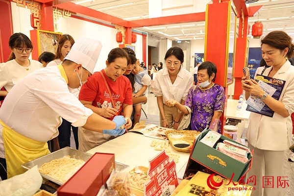 演出前，在天津桂發(fā)祥十八街麻花制作技藝非遺體驗(yàn)展臺(tái)前，泰國(guó)民眾體驗(yàn)天津麻花制作。人民網(wǎng)記者 楊一攝
