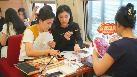 10月1日，旅客們在G1634次列車上給油紙傘作畫。新華社記者周義 攝