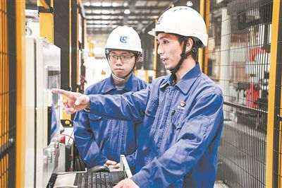 在廣西柳工機(jī)械股份有限公司生產(chǎn)車間內(nèi)，一名高級技師（右）給徒弟講解數(shù)控設(shè)備操作細(xì)節(jié)。新華社記者 曹祎銘攝