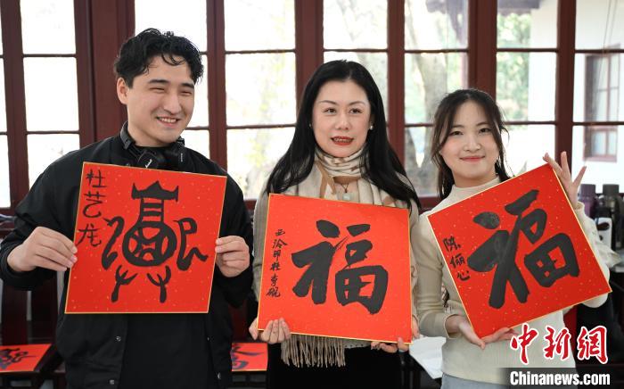 1月20日，外籍留學(xué)生和西泠印社社員李硯(中)展示各自創(chuàng)作的福貼。當(dāng)日，來自巴西、馬來西亞、加納、哈薩克斯坦的外籍留學(xué)生在浙江杭州西泠印社體驗福貼、春聯(lián)和篆刻，感受古老的中國傳統(tǒng)文化。中新社記者 王剛 攝