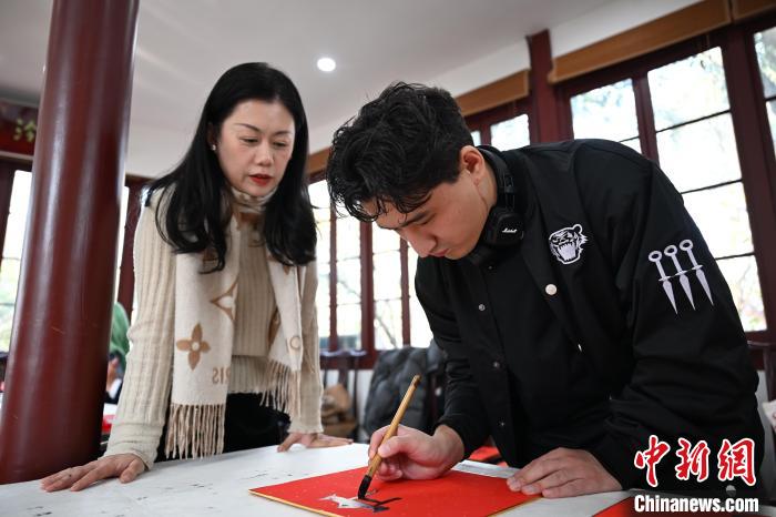 1月20日，外籍留學(xué)生在西泠印社社員李硯指導(dǎo)下寫福。當(dāng)日，來自巴西、馬來西亞、加納、哈薩克斯坦的外籍留學(xué)生在浙江杭州西泠印社體驗福貼、春聯(lián)和篆刻，感受古老的中國傳統(tǒng)文化。中新社記者 王剛 攝